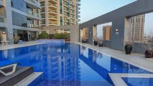 Una piscina con agua azul cristalina, rodeada de edificios modernos y plantas en macetas.