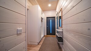 A narrow hallway with wooden walls, a white door at the end, and a small shelf with items on the right. - Pitkäkuusen mökki, new cabin close to center of Äkäslompolo. Nature in backyard (Lappi)