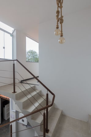 Un interior moderno con una escalera, una lámpara colgante y vistas al exterior.