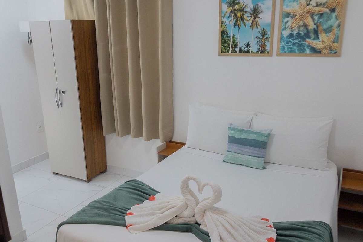 Ein Hotelzimmer mit einem Bett, einem Kleiderschrank, einem Vorhang, einer Wand-Klimaanlage und zwei Bildern.