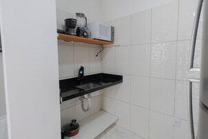 Una cocina con encimera negra, pileta de acero inoxidable y salpicadero blanco de azulejos.