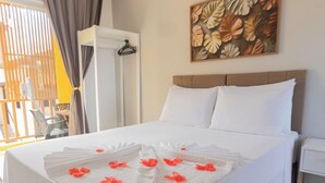 A hotel room with a bed, white linens, a painting, and a window with curtains.