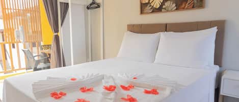 A hotel room with a bed, white linens, a painting, and a window with curtains.