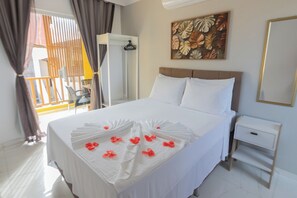 A hotel room with a bed, a nightstand, a painting, and a view of the outside.
