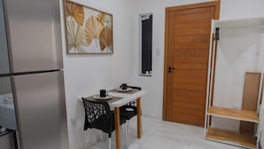 A compact kitchen with a refrigerator, a dining table with chairs, and a wooden door.