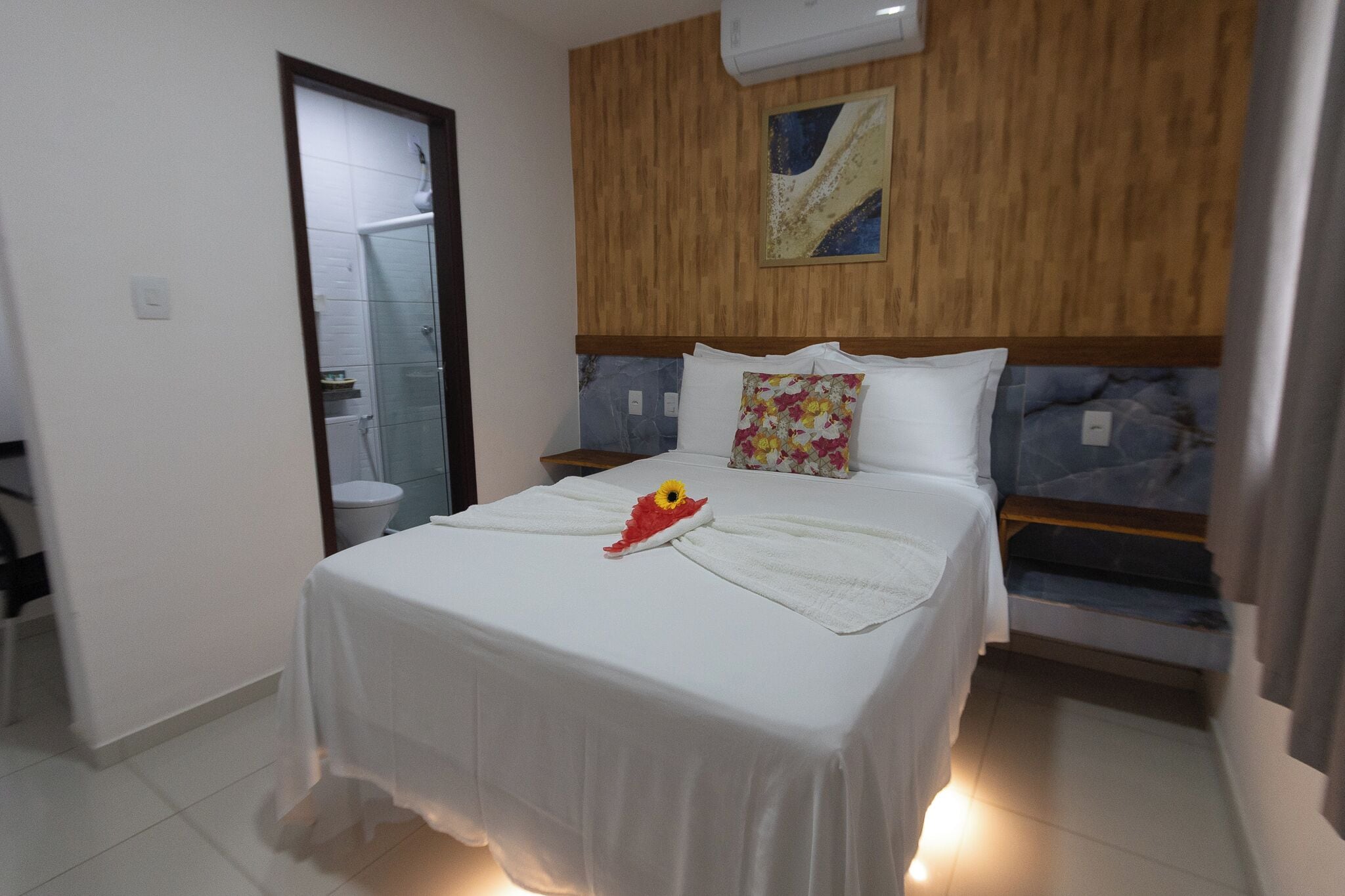 Una habitación de hotel con cama, mesita de noche, ducha y baño.