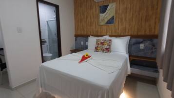 Una habitación de hotel con cama, mesita de noche, ducha y baño.