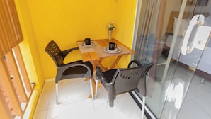 A small dining area with a table and two chairs, a vase with flowers, and a glass partition.