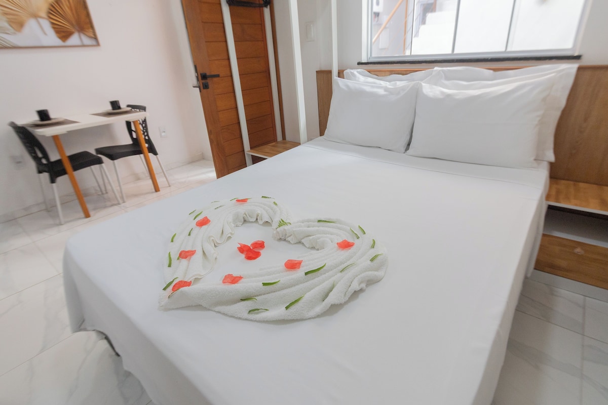 Ein Hotelzimmer mit einem ordentlich bezogenen Bett, einem kleinen Schreibtisch mit Stuhl und einem Fenster mit Blick.