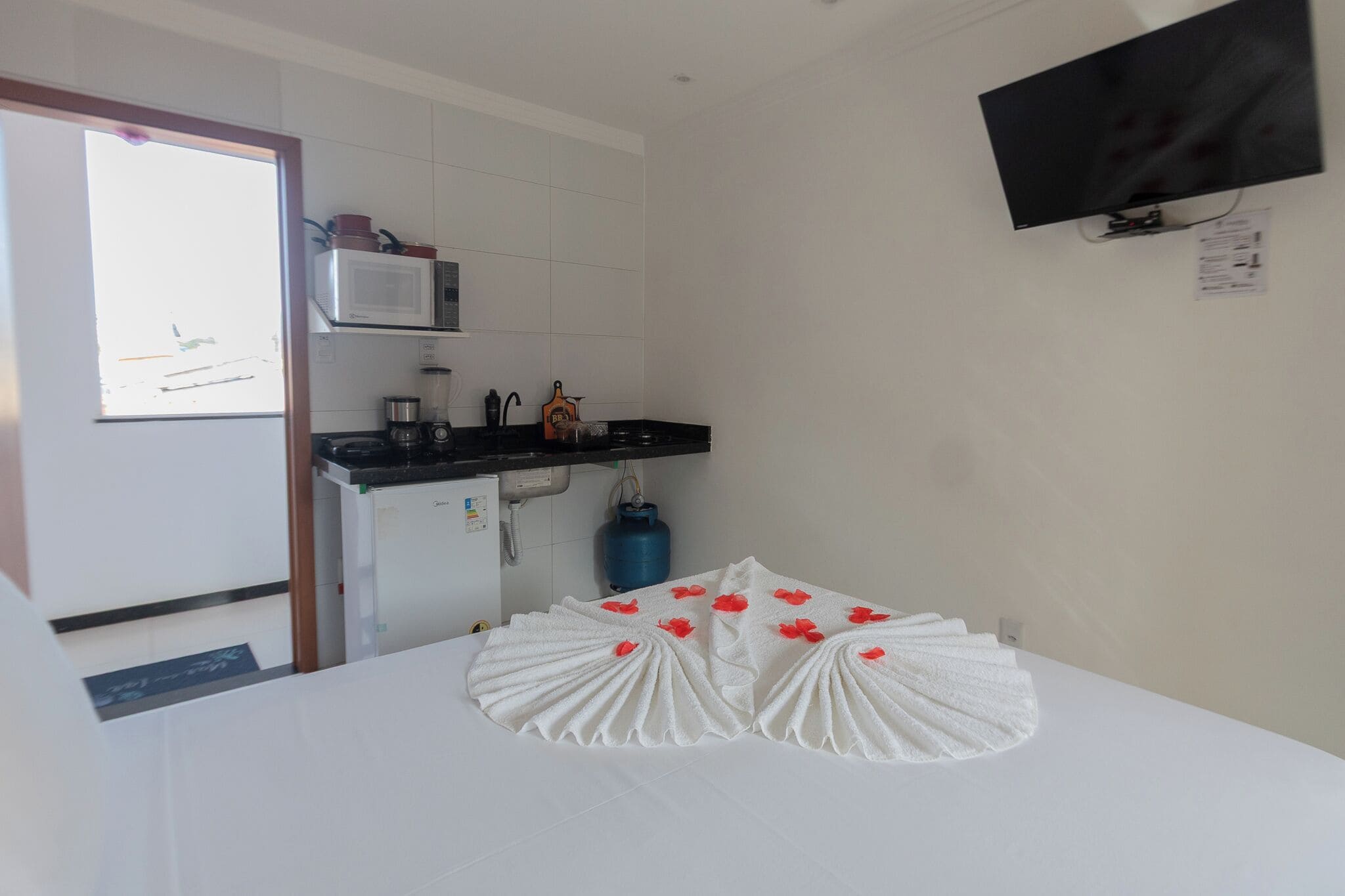 Une chambre d’hôtel équipée d’un lit, d’une kitchenette, d’une télévision et d’un chauffe-eau.
