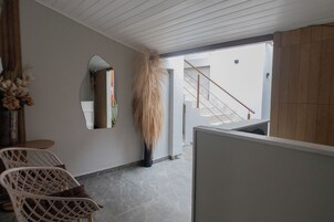 Un interior moderno con una escalera, una planta alta y un rincón de estar con sillas.