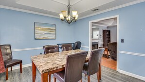 A dining room with a marble table, leather chairs, and a chandelier.