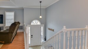 A staircase with white balusters leading to a door with a "WELCOME" sign.