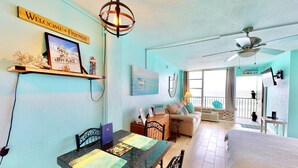 A room with a dining table, a bed, a ceiling fan, and a balcony with a view. - Daytona Beach XII (Daytona Beach)