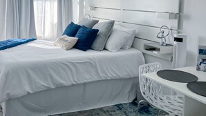 A modern hotel room with a large bed, white bedding, and a white headboard. - Daytona Beach XII (Daytona Beach)