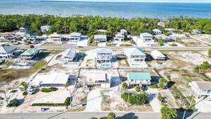 An aerial view of a coastal residential area with houses, some with pools, and a road in the foreground. - New- Beach Break East Gorrie- Pet Friendly (Saint George Island)