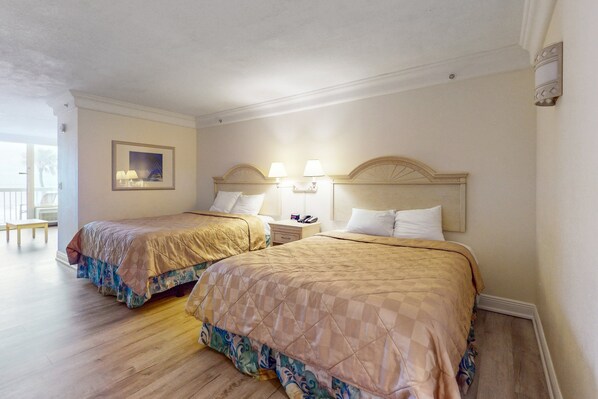 A hotel room with two beds, a nightstand, a lamp, and a framed picture on the wall. - Daytona Beach (Daytona Beach)