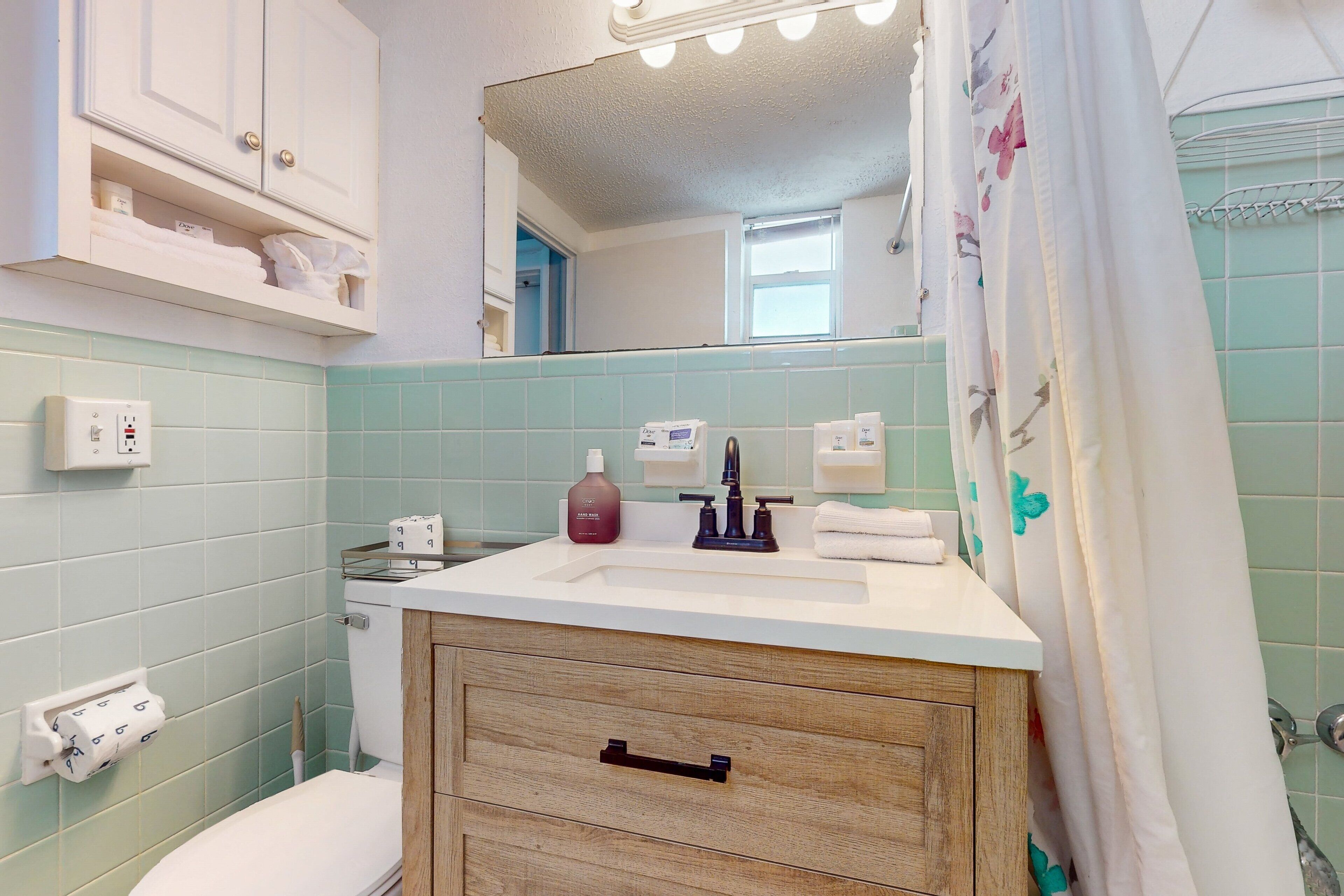 A bathroom with a white sink, a mirror above it, and a shower curtain with floral patterns.
