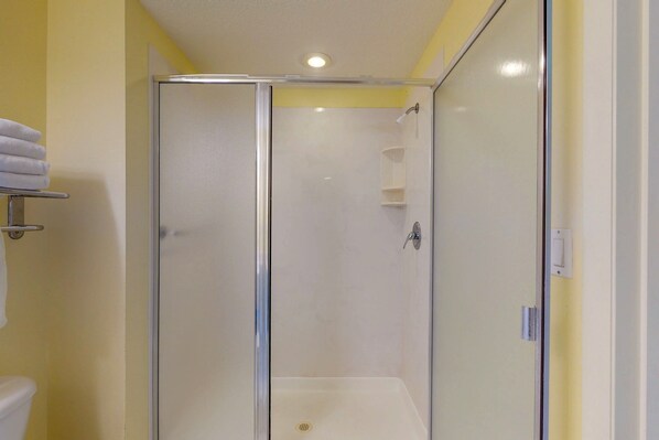 Une salle de bain avec une douche à parois de verre, des toilettes et un porte-serviettes.