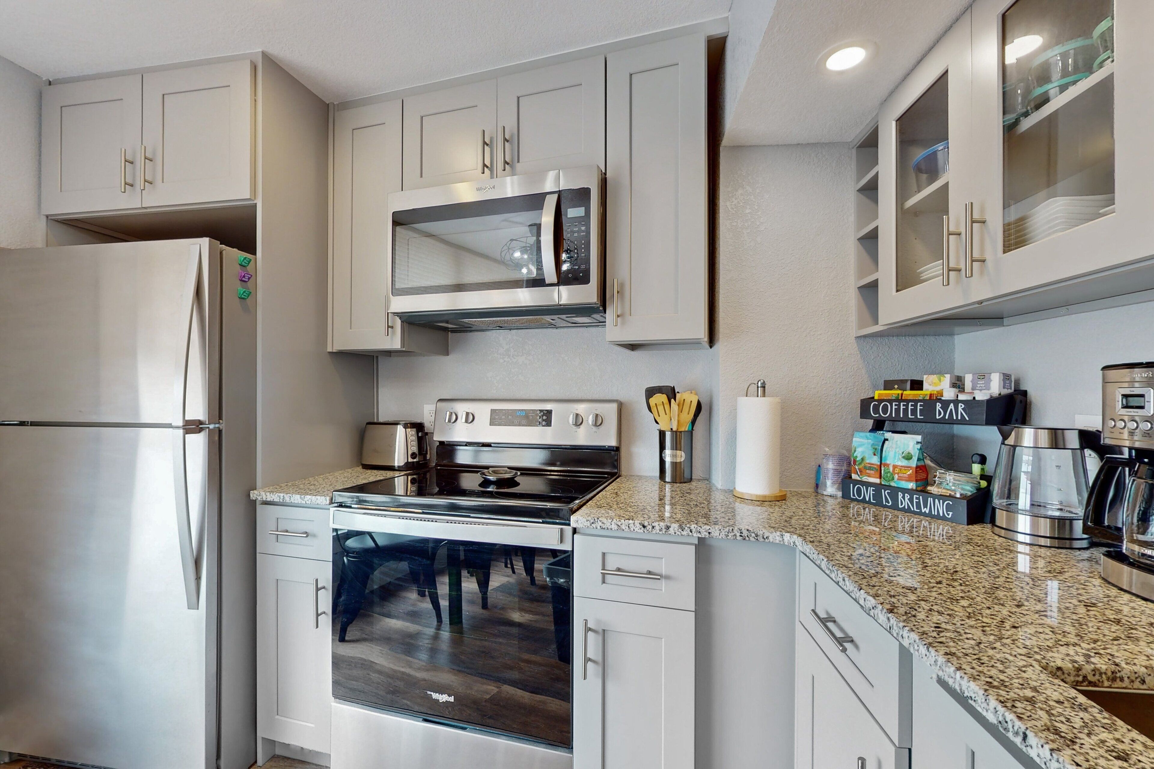 A modern kitchen with stainless steel appliances, white cabinetry, and granite countertops.