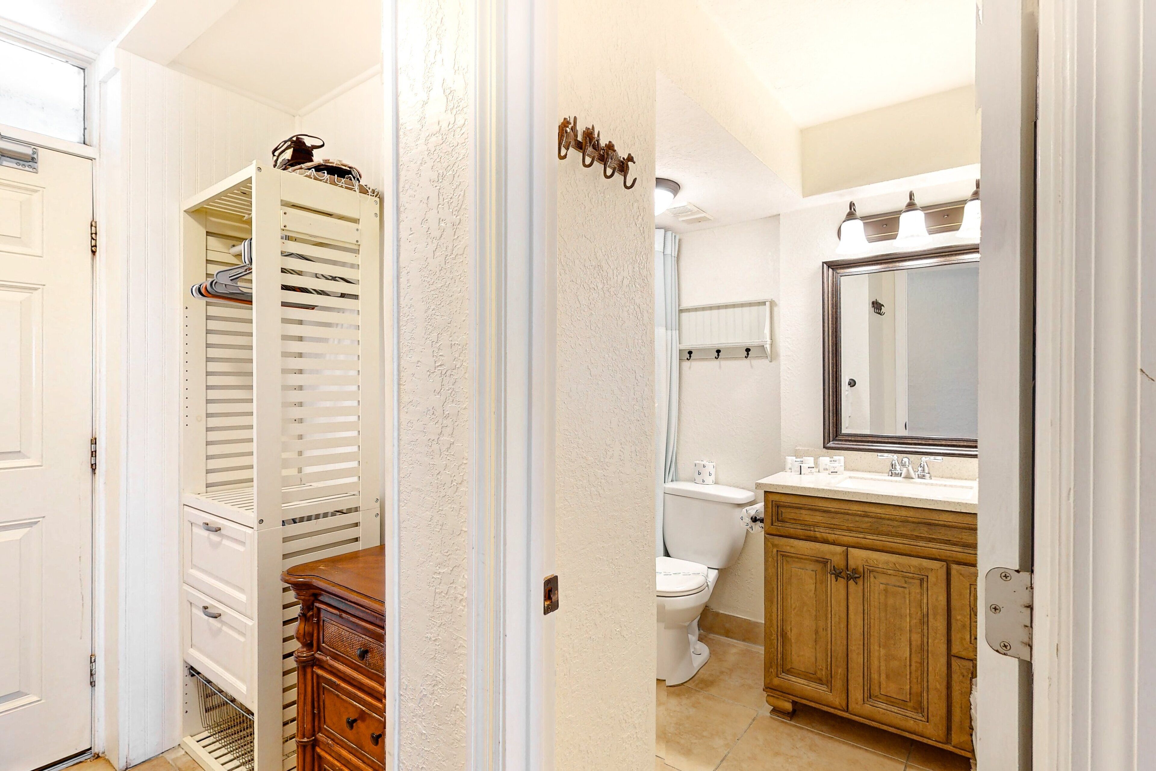 A bathroom with a toilet, sink, mirror, and wooden cabinet.