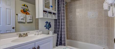 Une salle de bain avec un lavabo blanc, des toilettes, une baignoire et un rideau de douche.