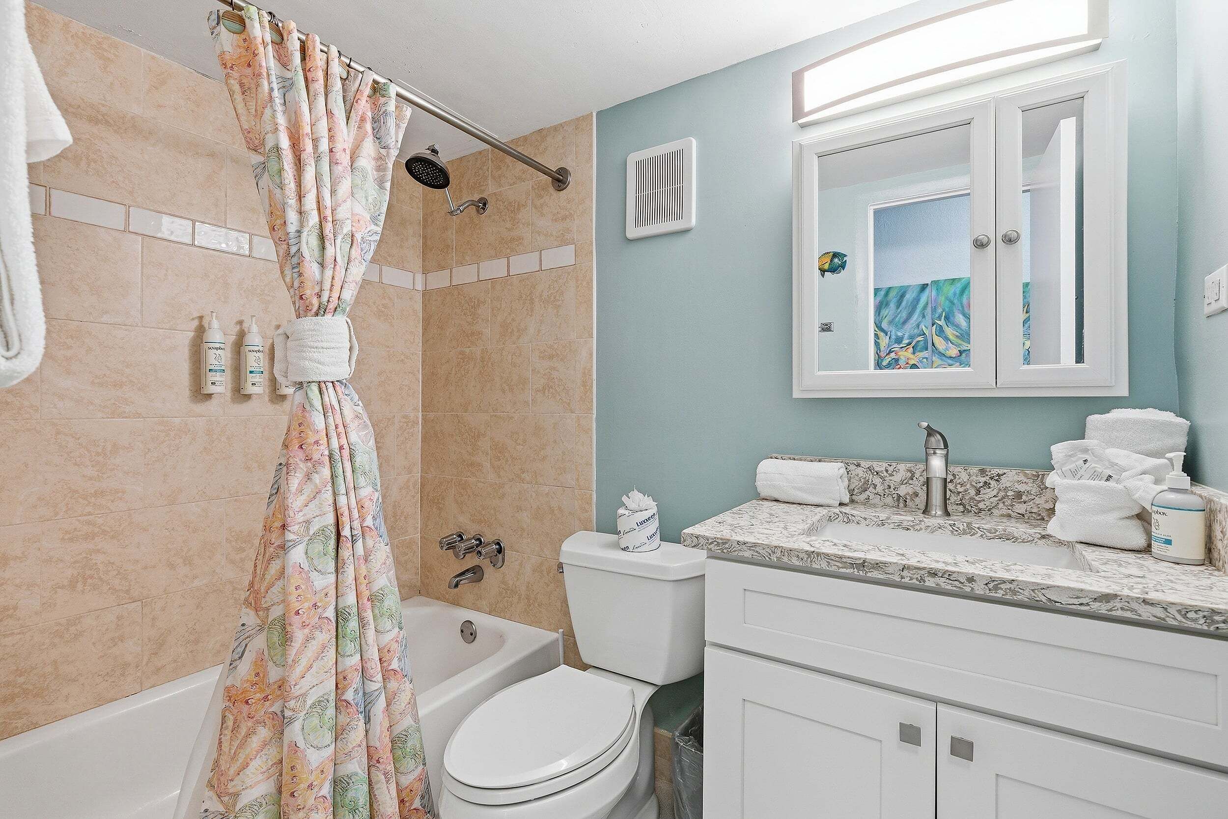 Une salle de bain avec une baignoire, des toilettes et un lavabo, avec un miroir au-dessus.