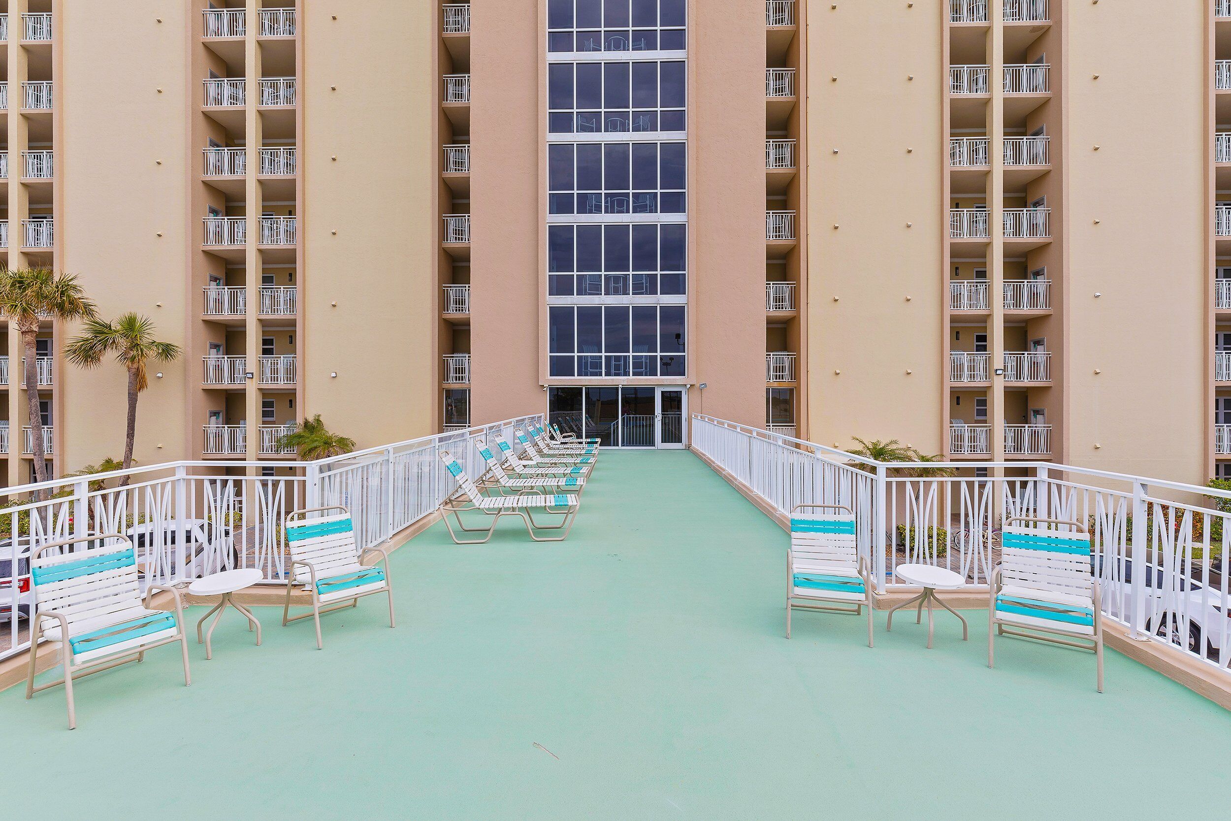 A hotel with a central atrium, rows of balconies, and outdoor seating areas.