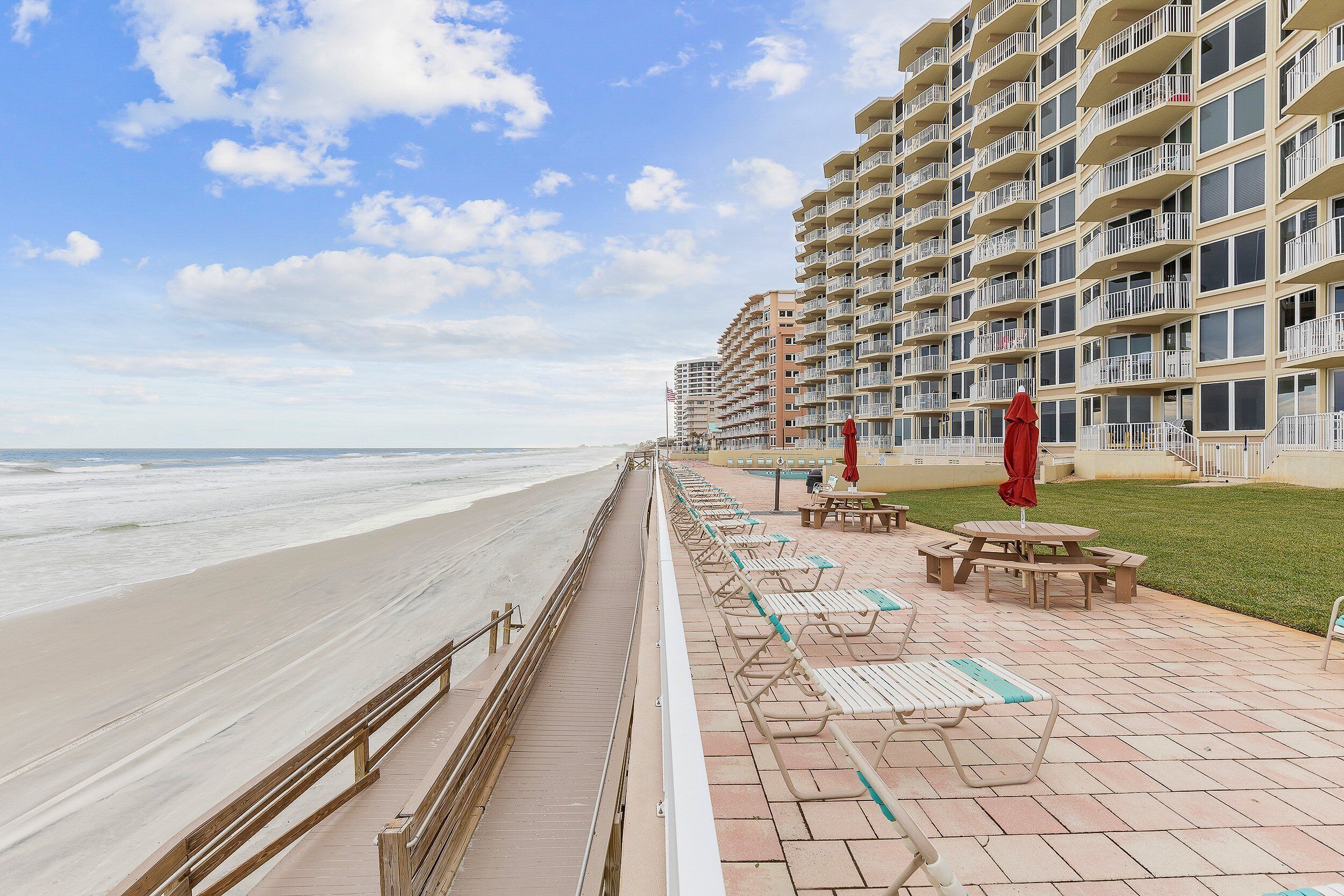 Un hotel frente a la playa con paseo marítimo, asientos al aire libre y vista al océano.
