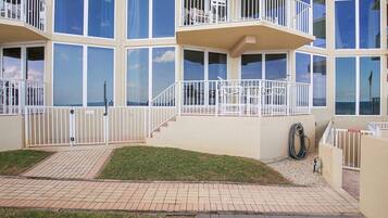 A multi-story building with balconies, large windows, and a paved entrance area.