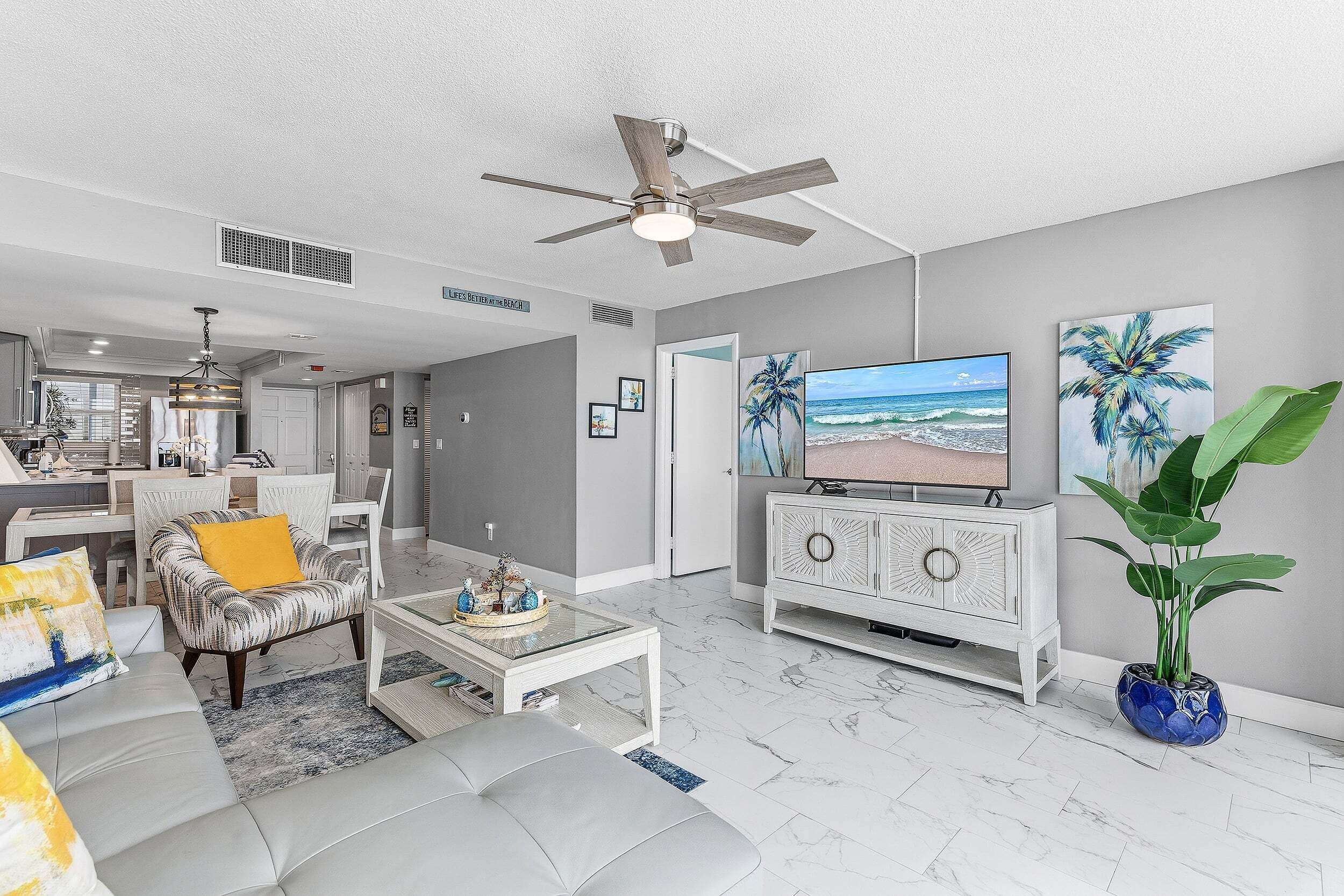 A living room with a ceiling fan, a television, a sofa, a coffee table, and a cabinet.