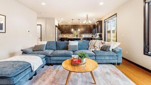 A modern living room with a sectional sofa, a coffee table, and a view into the kitchen. - Beautiful and Pristine 4b/2.5b Home in Prime Lynnwood/Martha Lake Location (Lynnwood)