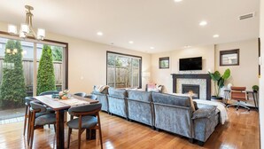 A spacious living room with a wooden dining table, grey sofa, and a fireplace. - Beautiful and Pristine 4b/2.5b Home in Prime Lynnwood/Martha Lake Location (Lynnwood)