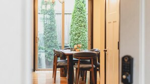 A hallway leading to a dining area with a wooden floor, a chandelier, and a view of a green tree outside. - Beautiful and Pristine 4b/2.5b Home in Prime Lynnwood/Martha Lake Location (Lynnwood)