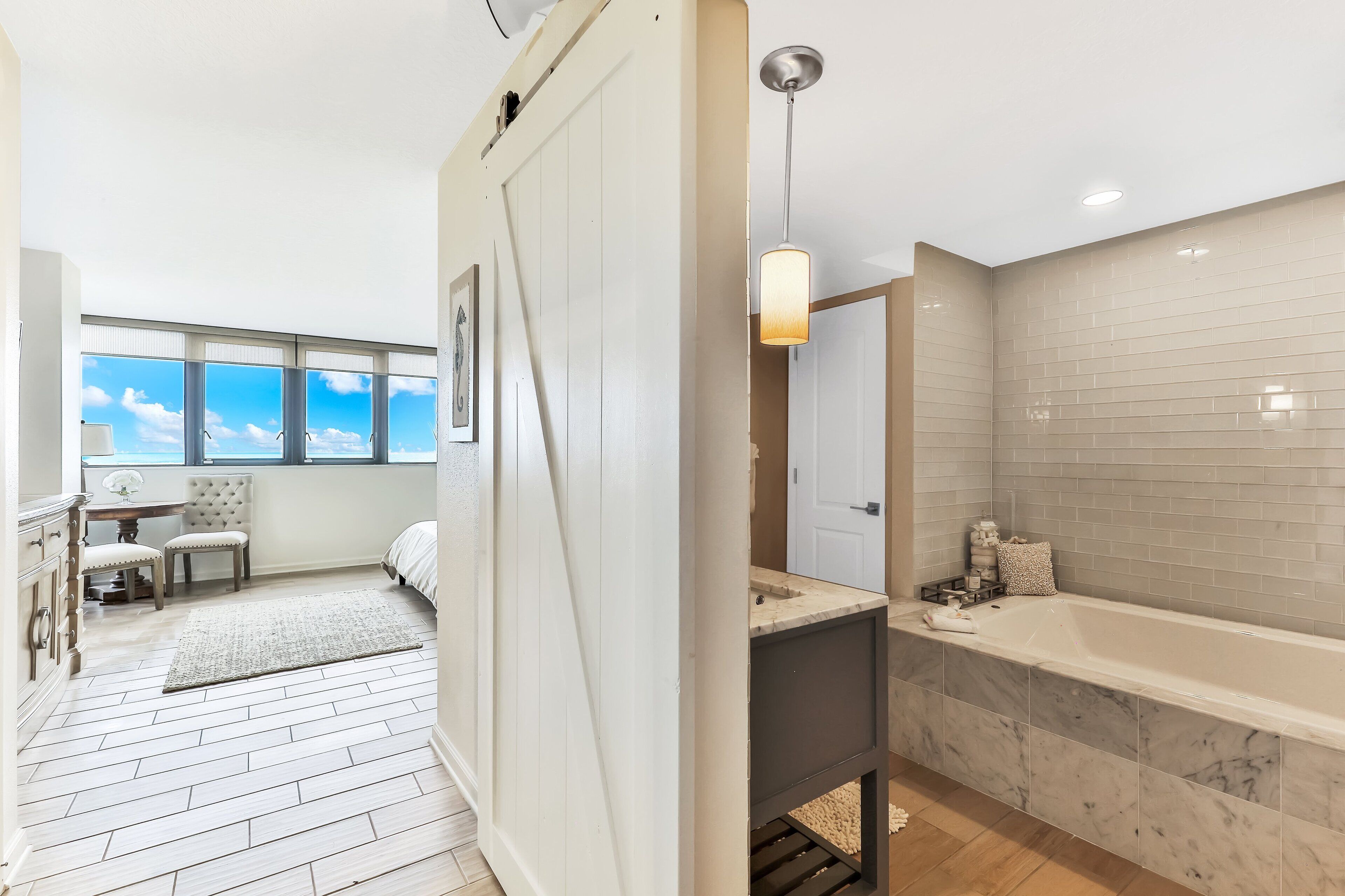 A modern bathroom with a large bathtub, a vanity, and a window with a view of the sky.