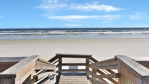 A wooden boardwalk leading to a sandy beach with the ocean in the background. - Castle Reef I (New Smyrna Beach)