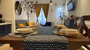 A modern dining area with a central table, chairs, and a television on the wall. - Carmel loft in Val'Quirico inside Villa Alessandra (San Miguel Xoxtla)