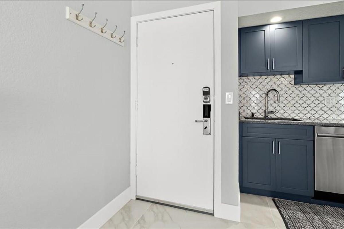 A kitchen with dark cabinets, a stainless steel sink, and a tiled backsplash.