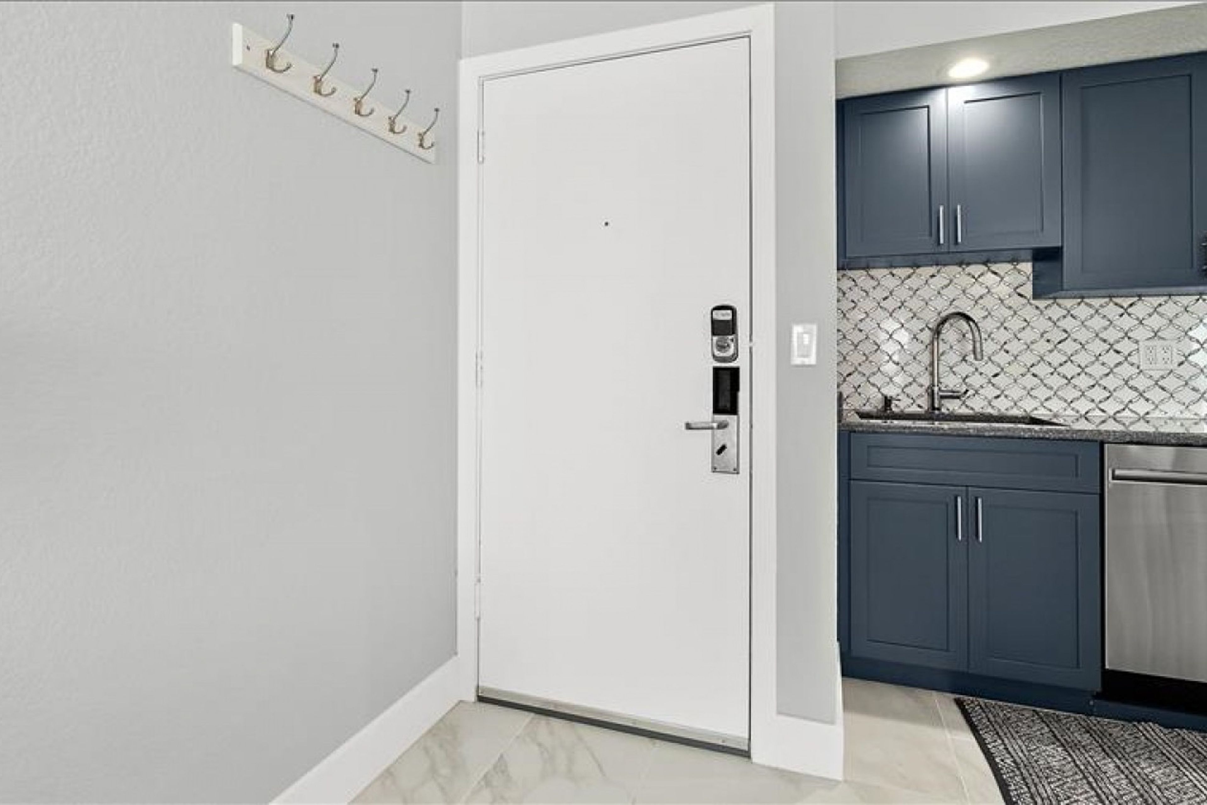 Una cocina con gabinetes oscuros, un lavamanos de acero inoxidable y un salpicadero de azulejos.
