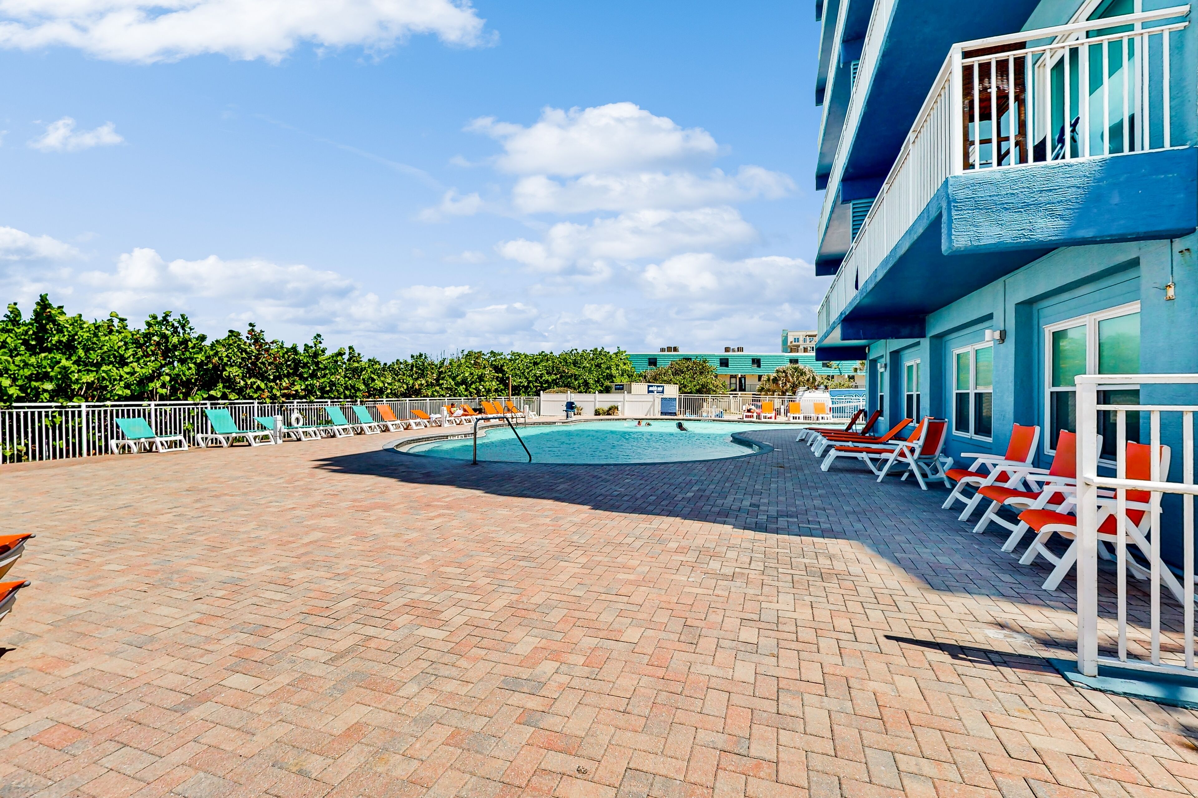 A pool area with lounge chairs and a brick floor.