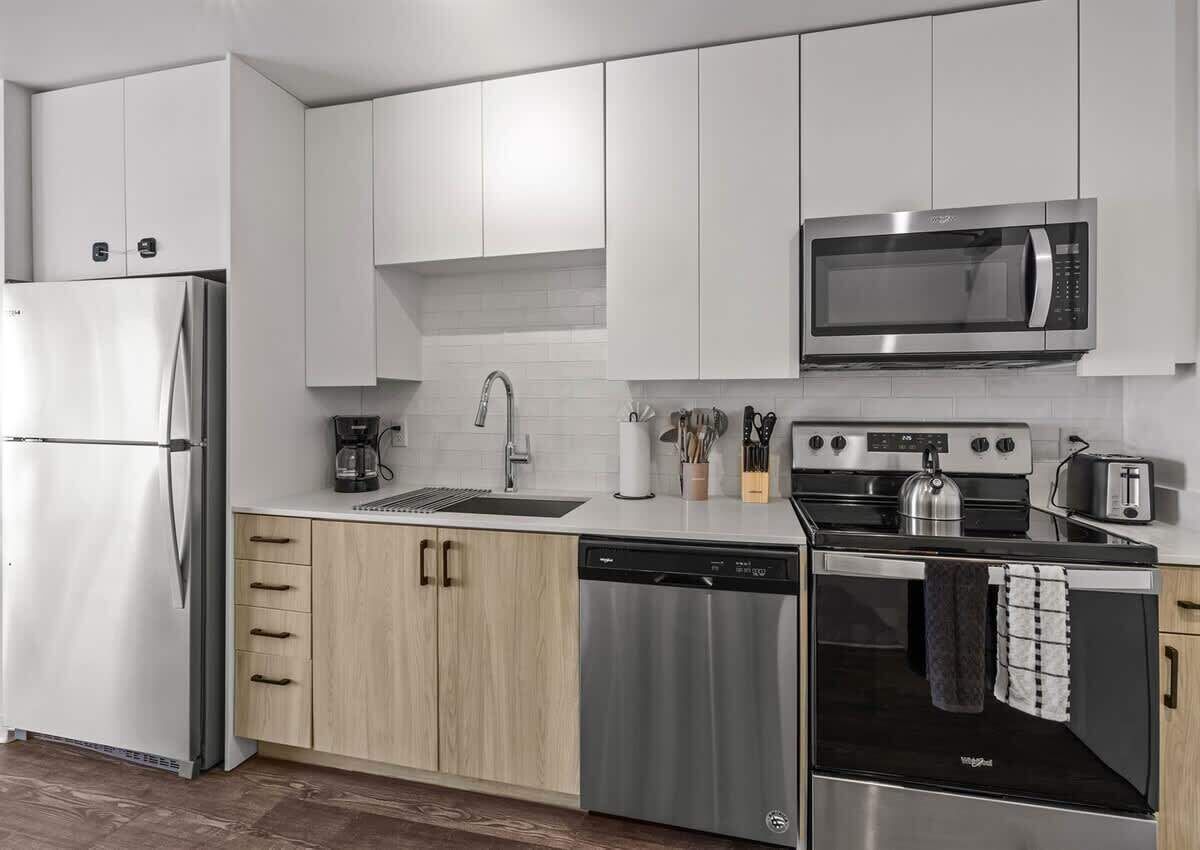 Una cocina moderna con armarios blancos, electrodomésticos de acero inoxidable y lavavajillas.
