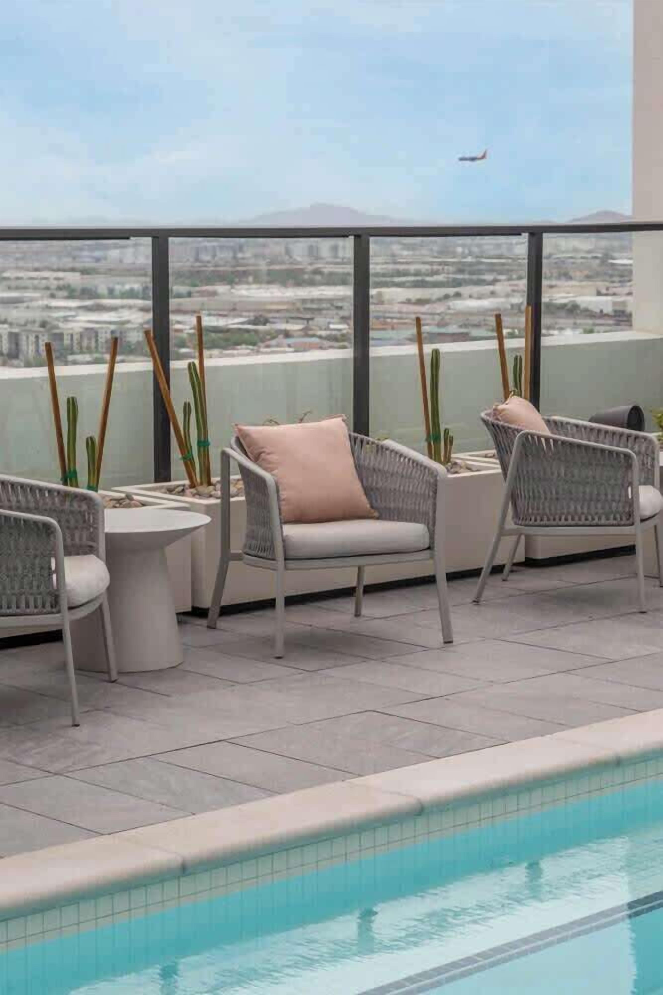 A poolside area with wicker furniture and a view of the cityscape.