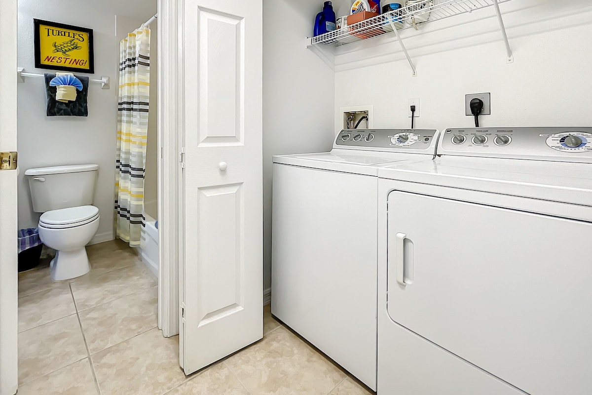 Un cuarto de lavandería con lavadora, secadora y un estante con productos de limpieza.