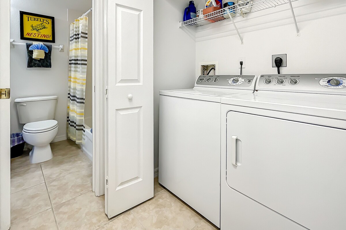 A laundry room with a washing machine, a dryer, and a shelf with cleaning supplies.
