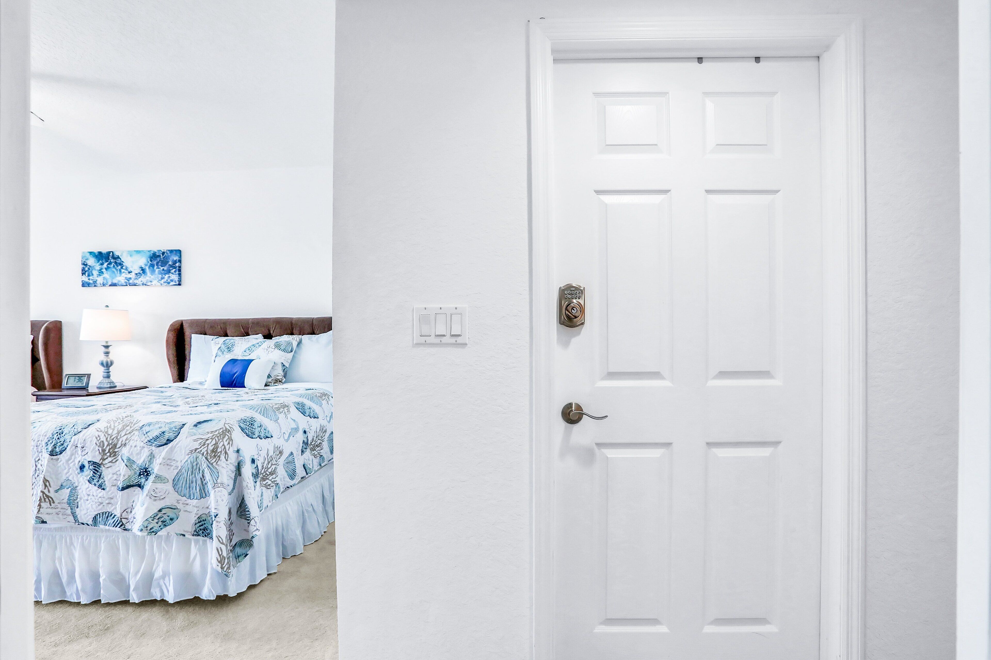 A bedroom with a bed, a nightstand, a lamp, and a wall-mounted artwork.