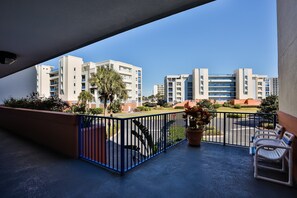 A balcony with a view of modern buildings, a blue railing, and a potted plant. - Oceanwalk (New Smyrna Beach)