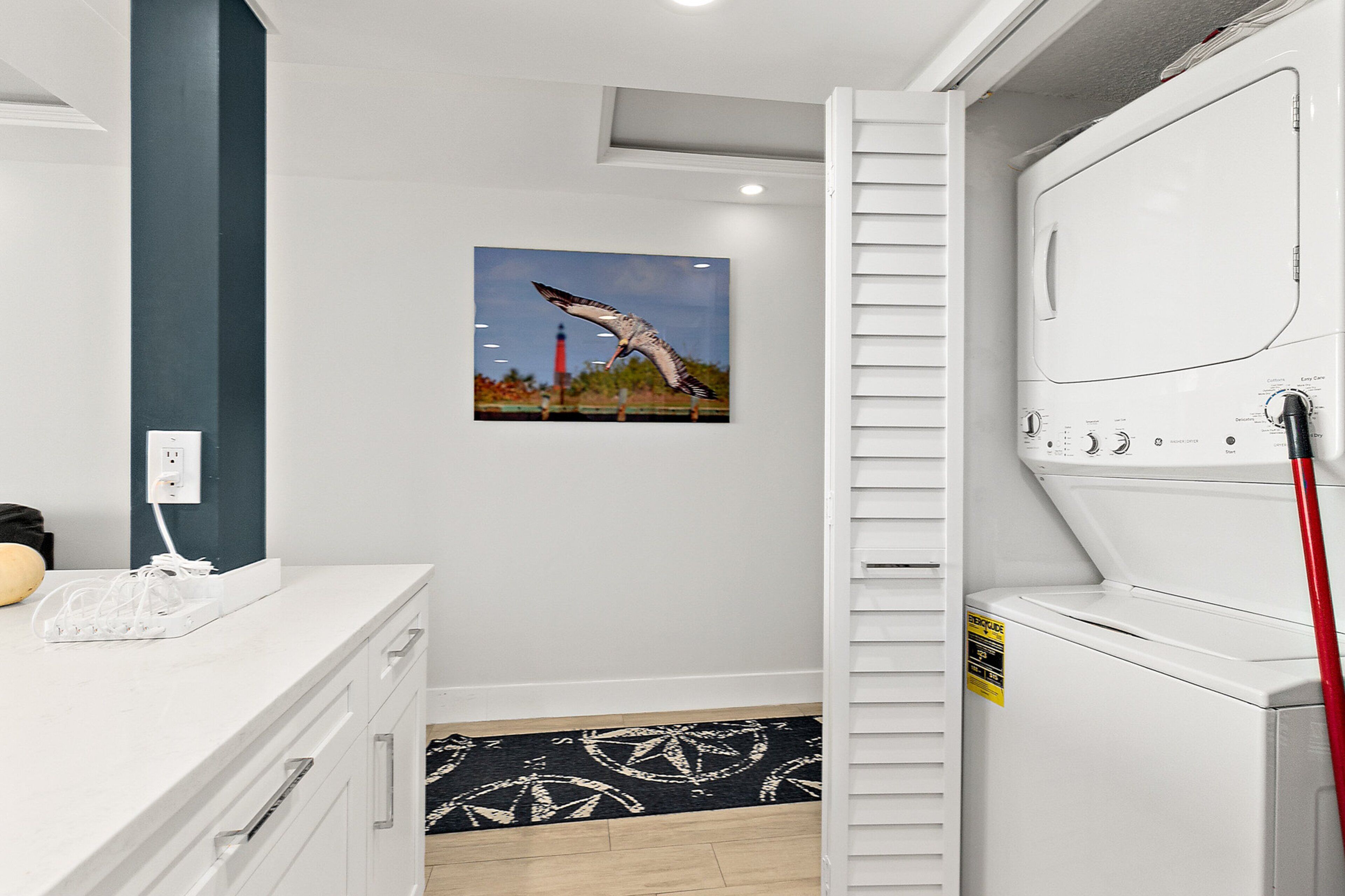 A laundry room with a washing machine, a dryer, and a wall-mounted rack.