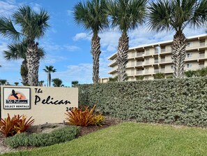 En skylt för ”The Pelican Select Rentals”, med en byggnad i bakgrunden.