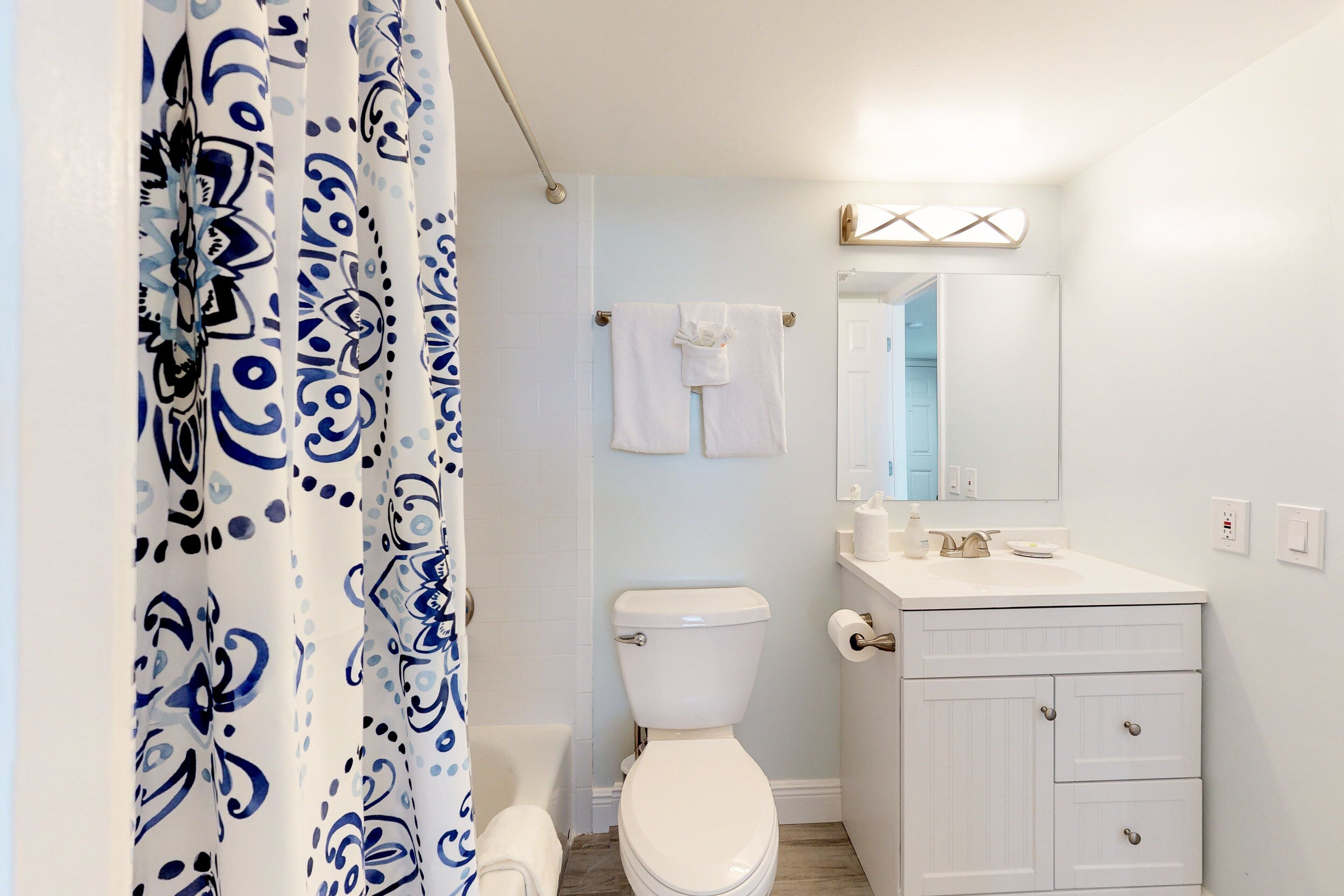 A bathroom with a toilet, a sink, and a mirror.