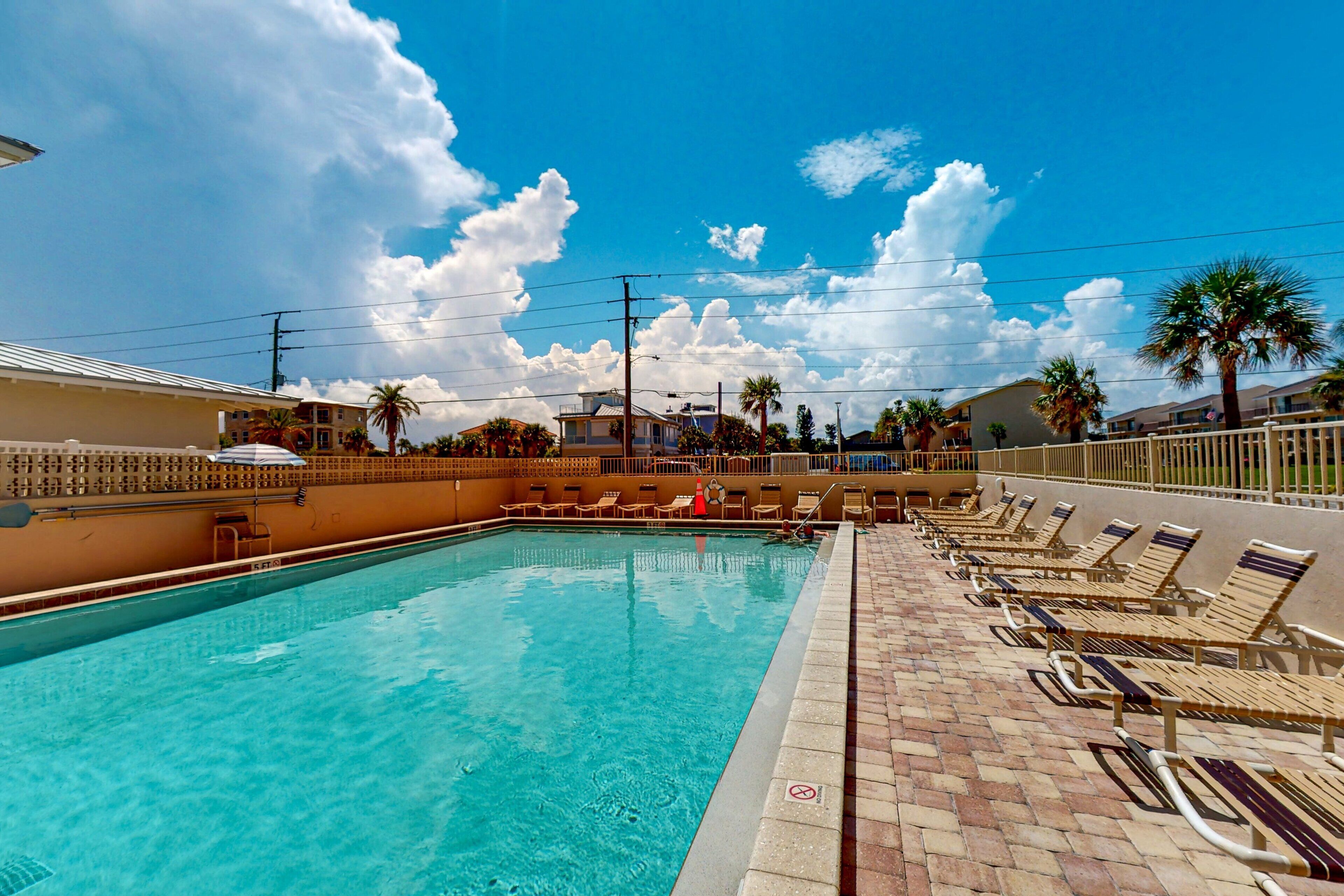 A swimming pool with lounge chairs and palm trees.